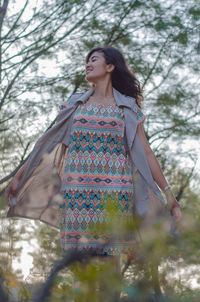 Low angle view of woman standing against trees