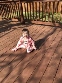 High angle view of girl sitting on wooden railing