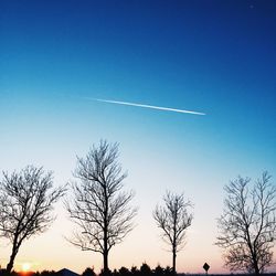 Low angle view of bare trees against clear blue sky