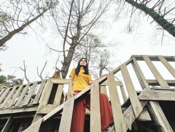 Low angle view of woman standing on staircase against tree