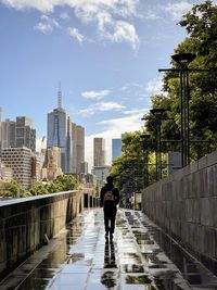 Rear view of man walking on street against sky