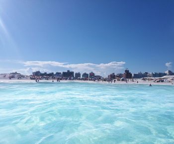 Scenic view of beach against blue sky on sunny day