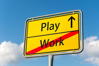 Low angle view of road sign against blue sky