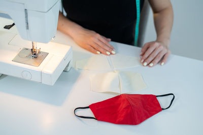 Midsection of woman holding textile by sewing machine