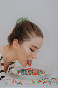 Close-up of woman with confetti against gray background