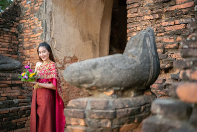 Portrait of woman standing against old temple