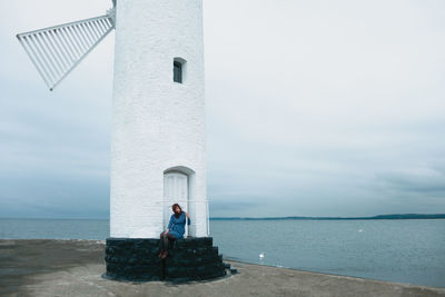 Rear view of man and woman by sea against sky