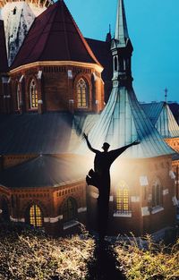 Rear view of man standing by building against sky