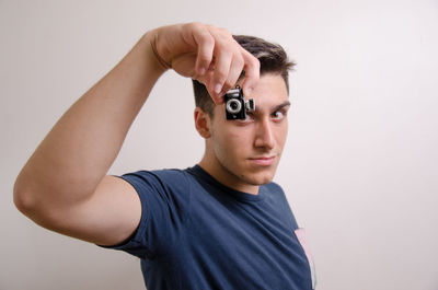 Portrait of young man standing against white background