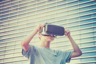 Boy wearing virtual reality simulator against building