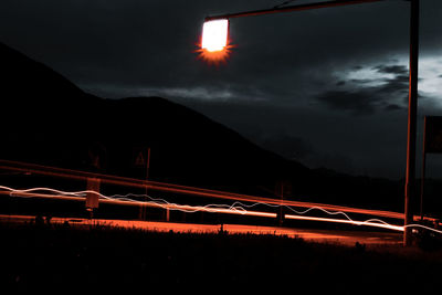 Light trails on road against sky at night