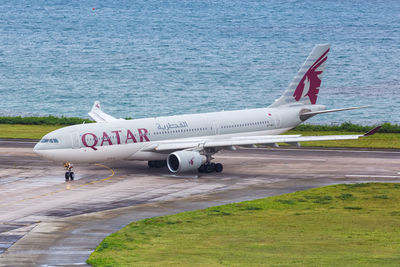 Airplane flying over airport runway against sky