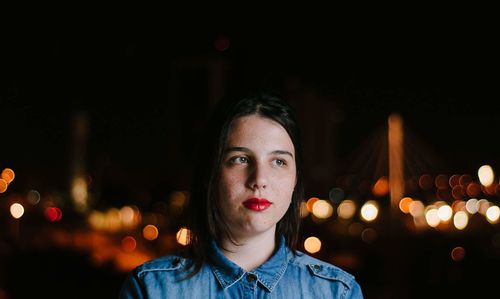 Thoughtful teenager in illuminated city at night