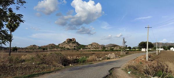 Panoramic view of road amidst field against sky