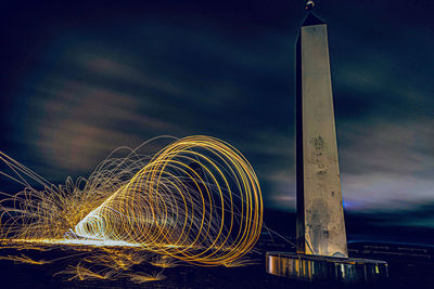 Low angle view of light trails against sky at night