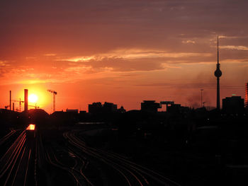 Railroad tracks in city against sky during sunset