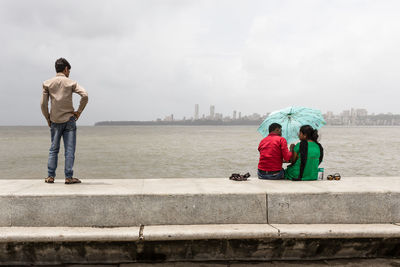 Rear view of people looking at cityscape against sky