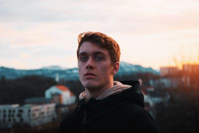 Portrait of young man looking away against sky during sunset