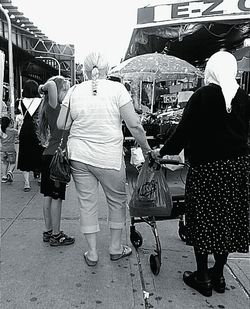 Rear view of people walking on street in city