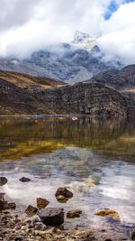 Scenic view of lake by snowcapped mountains against sky