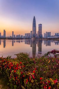 Scenic view of sea by buildings against sky during sunset