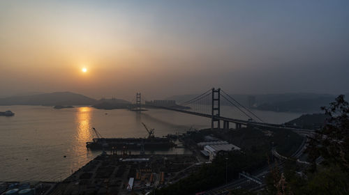 Bridge over sea against sky during sunset