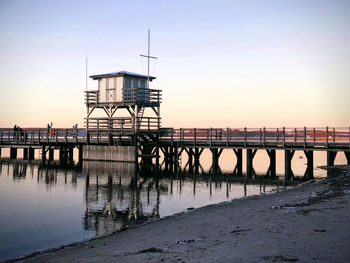 Pier over sea against sky during sunset