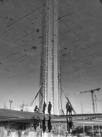 Low angle view of people at amusement park against sky