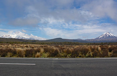 Scenic view of road by mountains against sky