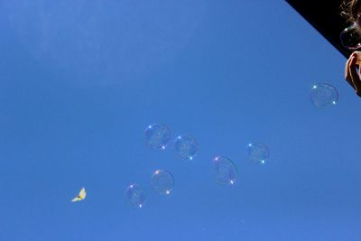 Low angle view of bubbles against blue sky