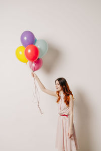 Woman holding balloons against white background