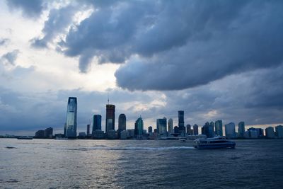 Sea and modern buildings in city against sky