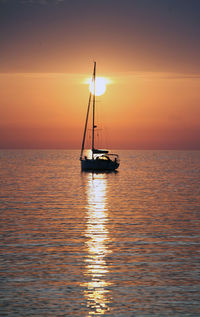 Sailboat on sea against romantic sky at sunset