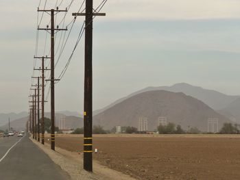 Electricity pylon and mountains against sky