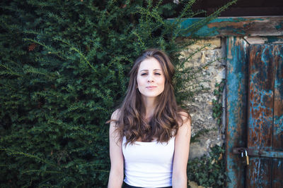 Portrait of young woman standing against plants