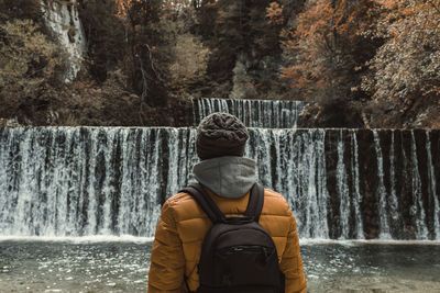 Rear view of man standing in front of waterfall