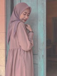 Young woman looking down while standing against wall