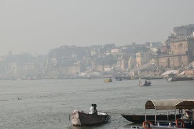 Boats moored on sea against buildings in city