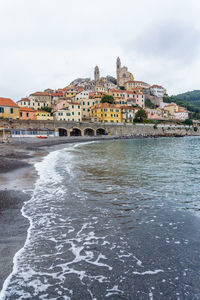 View of buildings by sea against sky in city