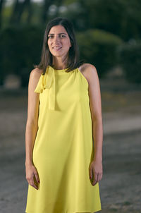 Portrait of woman standing against trees on road