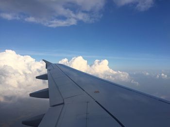 Low angle view of airplane wing over cloudscape