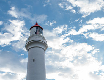 Low angle view of lighthouse by building against sky