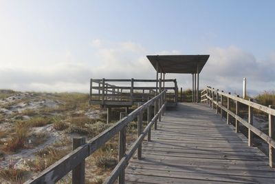 Footbridge at beach against sky during sunset