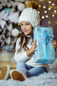 Portrait of cute girl sitting on bed at home