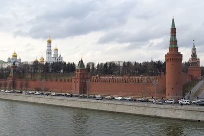 Bridge over river by buildings against sky in city