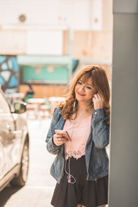 Young woman looking away while standing on mobile phone