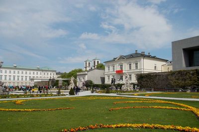 People in park by buildings against sky