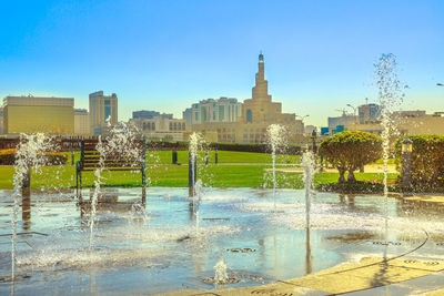 Fountain in city against clear sky