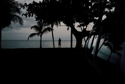 Silhouette people on beach against sky during sunset