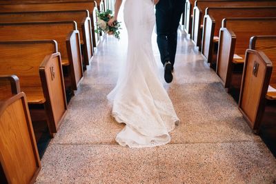 Low section of wedding couple walking on tiled floor in church